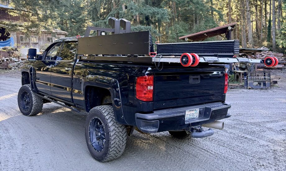 A black truck with its TUFFLIFT deck raised in a gravel yard