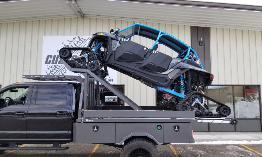A blue side-by-side being lifted on a TUFFLIFT deck outside the shop